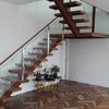 Escada interior com estrutura de metal ou madeira, degraus de madeira e corrimão de vidro